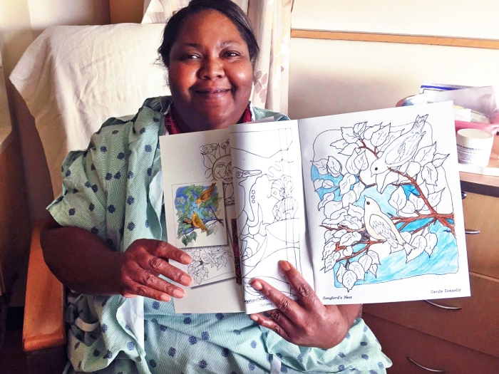 A patient smiles with a coloring book from the Bedside Art program