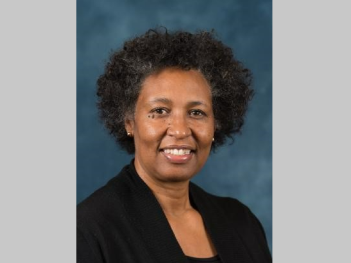 Professional portrait of a middle aged Black woman with short curly hair wearing a black blazer