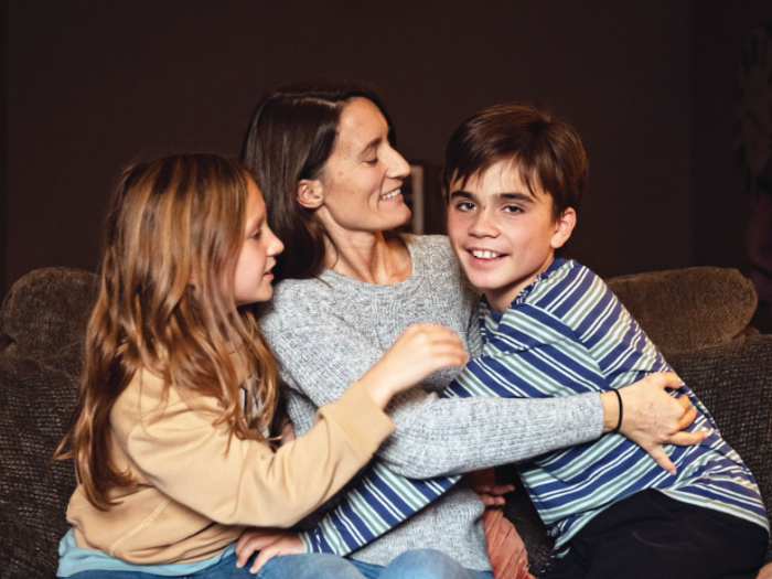 A mom snuggles with her two elementary-age children on a couch