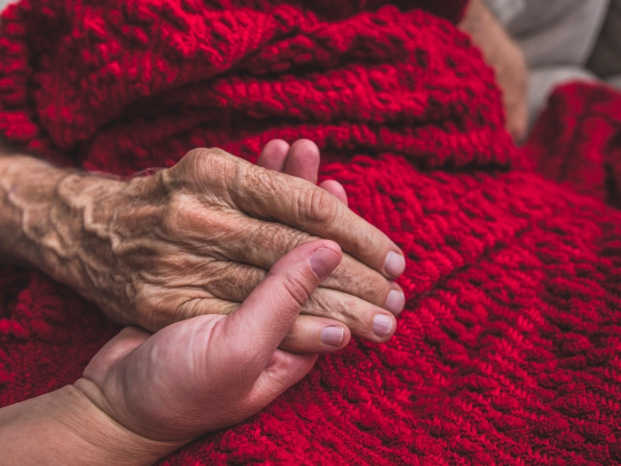 hand holding older hand over blanket