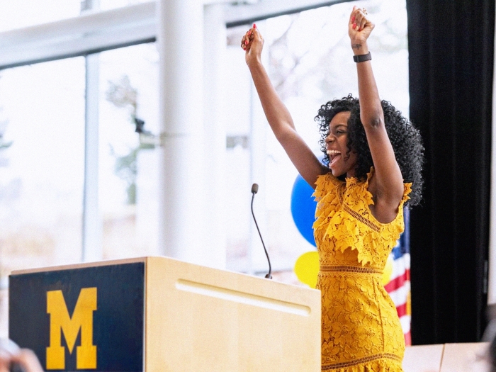 girl in yellow dress raising hands at podium
