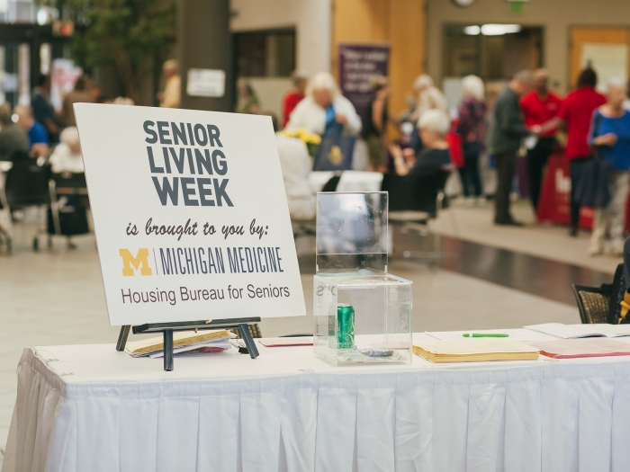 Table at event with sign on easel reading, Senior Living is brought to you by: Michigan Medicine - Housing Bureau for Seniors