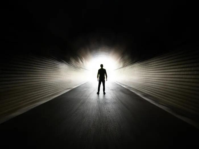 black room with person visual far away walking towards glowing light