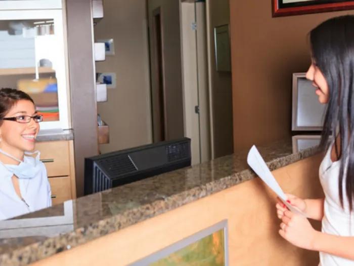 Stock photo of a young person talking with a front desk staff member