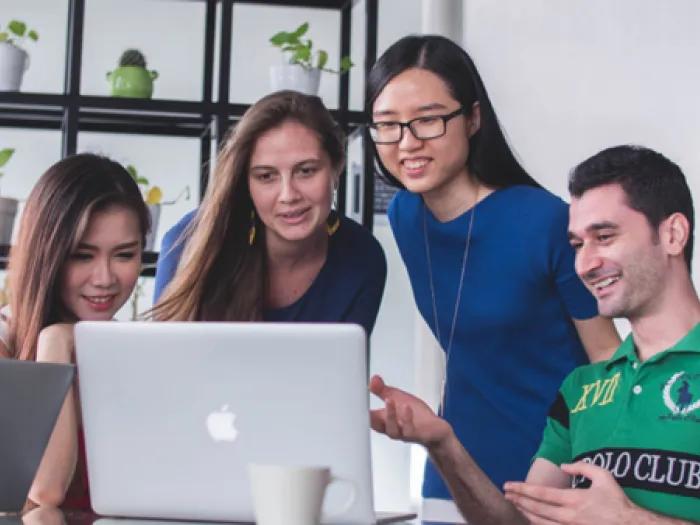 Stock photo of a group of young people sitting around a computer