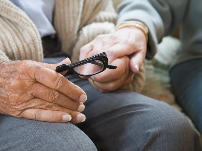 older woman holding glasses in lap
