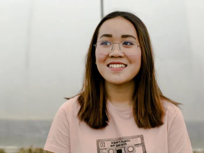Stock image of a young person looking off into the distance. They are wearing glasses and a pink graphic t-shirt.