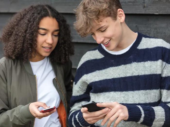 Stock photo of two young people looking at their phones together