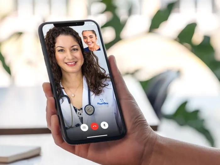 Stock image of a person holding an iPhone, which displays a telehealth conversation