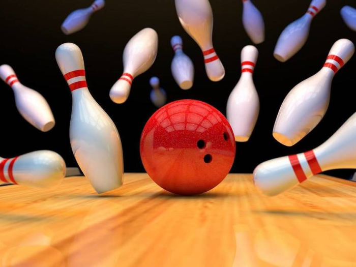red bowling ball knocking down bowling pins