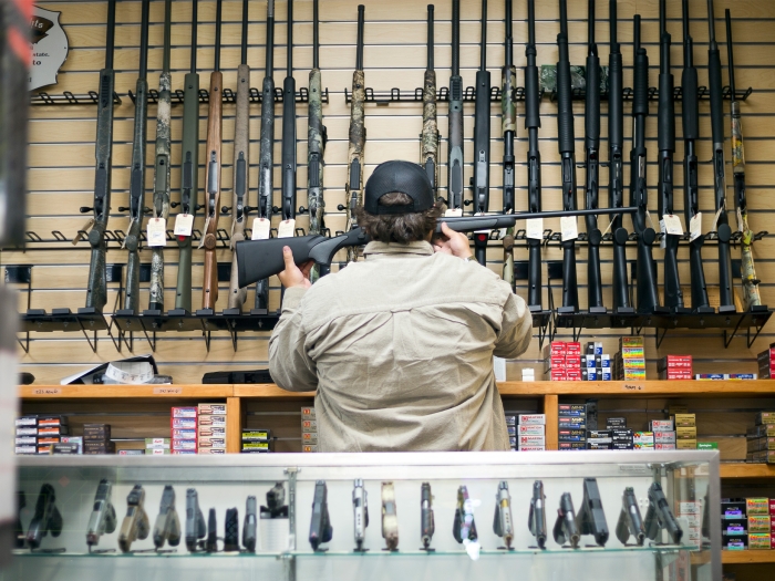 man looking at guns clerk store