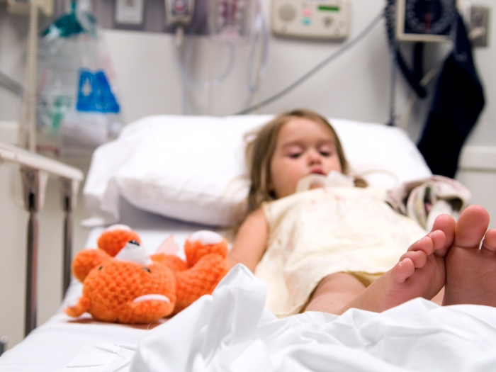 child in emergency room hospital bed with teddy bear 