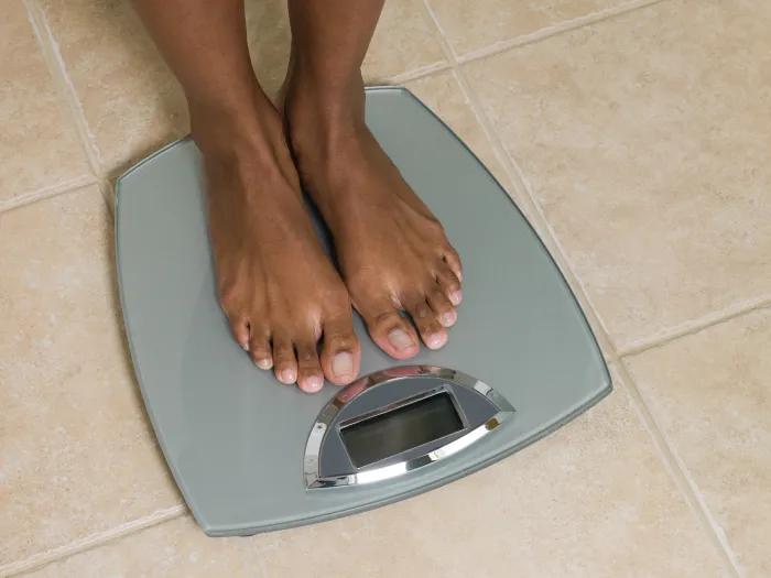 person's feet on scale on biege tile floor
