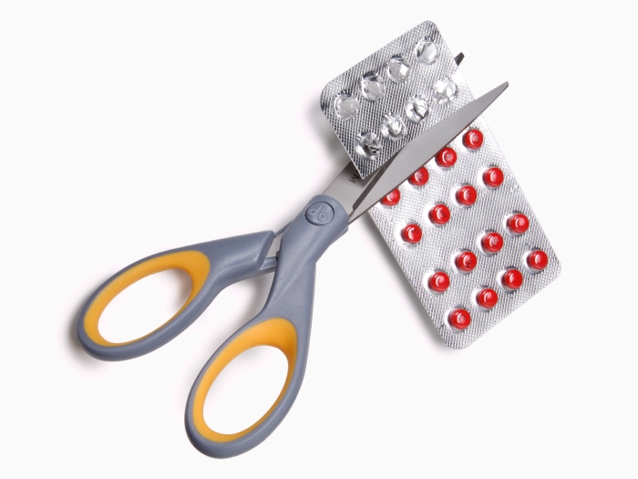 grey scissors cutting red pill back 