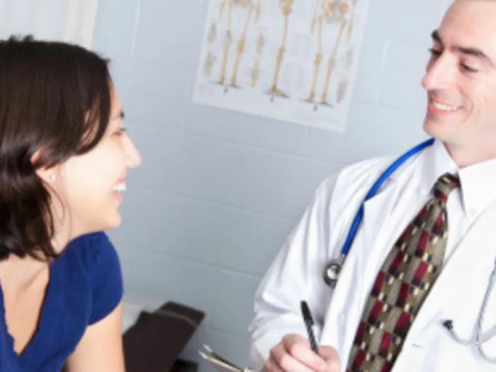 Teen smiles with doctor at exam