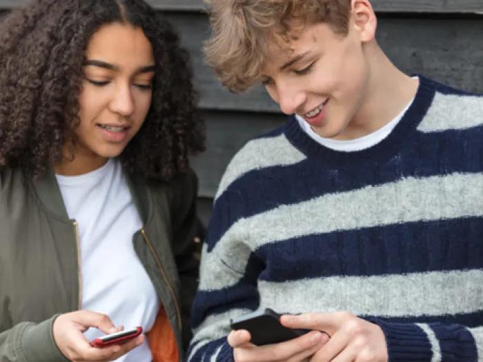 teen girl and boy look at their phones
