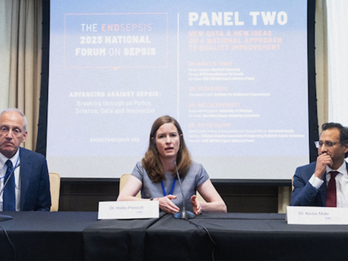 Hallie Prescott talking while sitting at a panel table with two individuals.