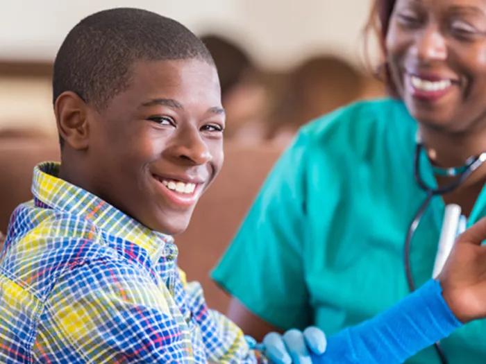 Teen boy smiles at camera while getting health exam