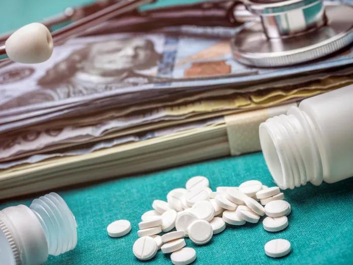 Spilled pills next to a stethoscope and pile of cash