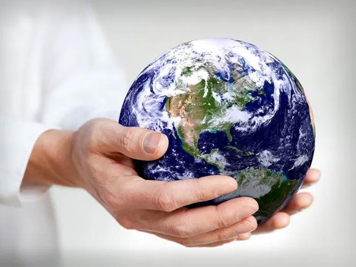 Hands holding a miniature version of the planet Earth. 