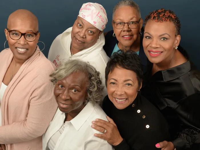 Group photo of six Black women who are breast cancer survivors. They are all looking up at the camera and smiling.