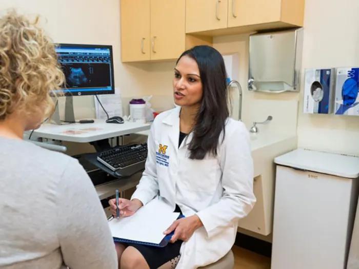 A doctor talks with a patient in an exam room.