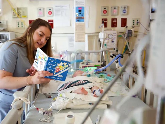 A Michigan Medicine employee reads to a baby in the Brandon Neonatal Intensive Care Unit.