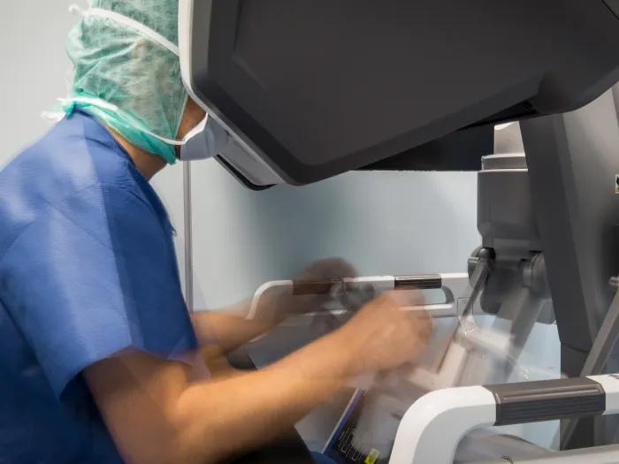 doctor looking into robotic set up in scrubs and scrub hat
