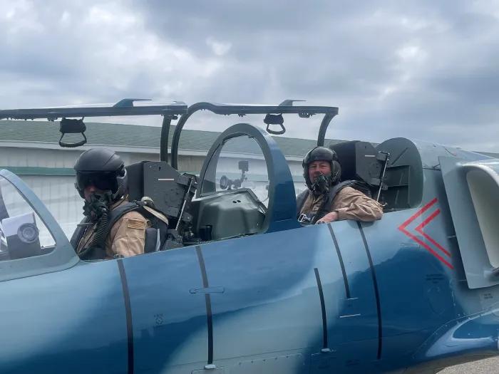 two men flying blue airplane outside in helmets