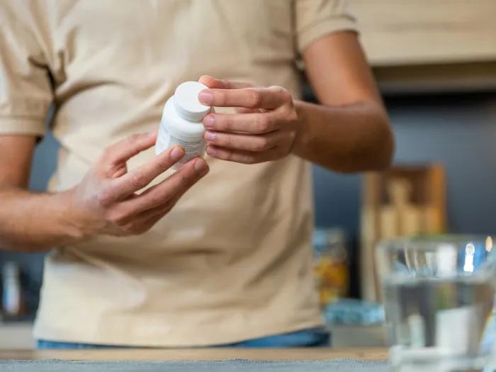 close up on person looking at bottle of pills with water in background