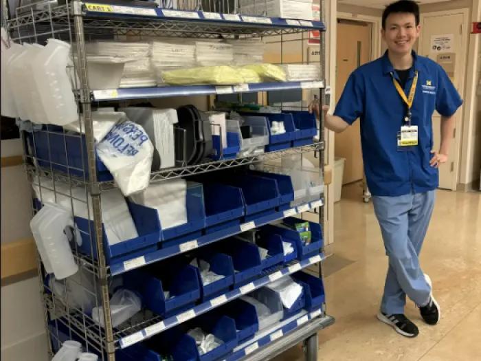 Volunteer standing next to a cart of medical supplies.