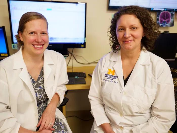 doctors sitting together smiling at camera in office with computer in background
