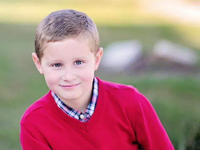 Smiling portrait of Jack Fineske. He has short brown hair and is wearing a red sweater.