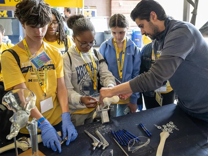 Group of diverse youth at Michigan Medicine youth summit exploring a hands-on exhibit