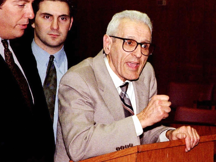 Kevorkian pounds his fist on a podium. His lawyers stand behind him.