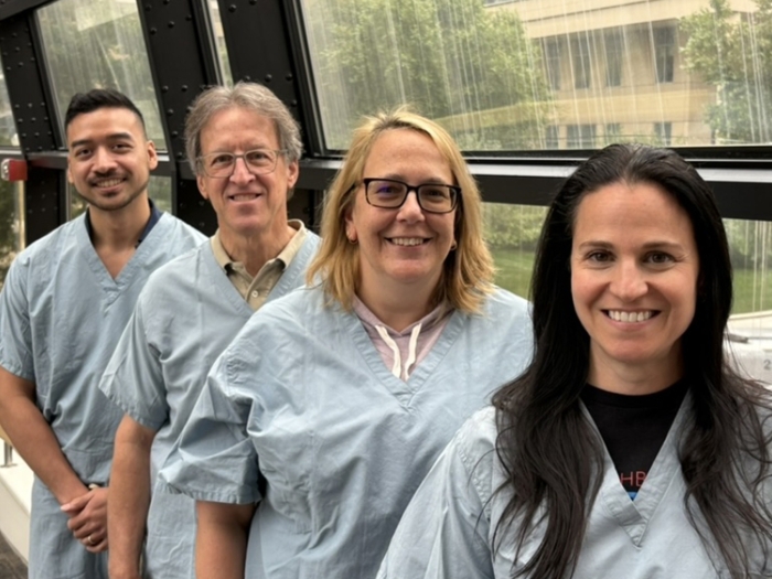 surgeons lined up smiling in tunnel hallway in blue scrubs