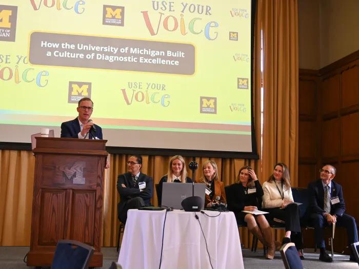 A panel sits on stage and speak