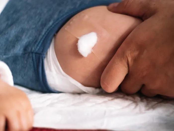 A child's leg with a bandage after receiving a shot.