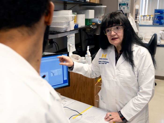 woman in white coat talking in lab with lab glasses on 