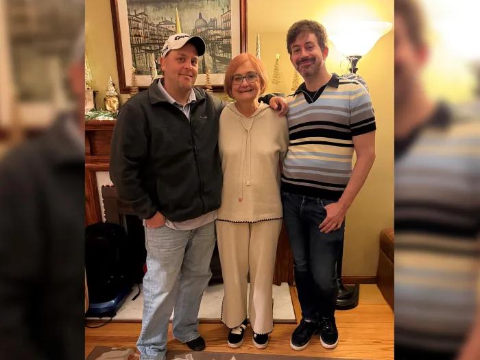 two sons posing with their mom in a living room standing