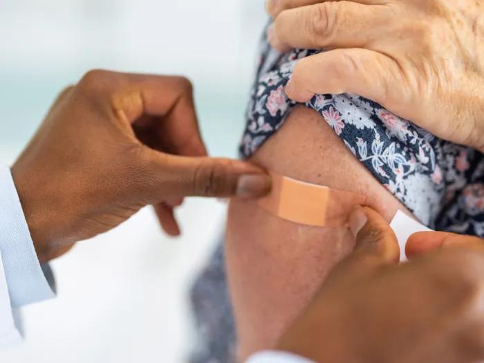 hand putting band aid on persons arm