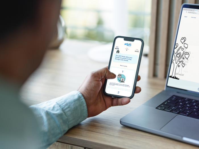 man holding iphone in hand over laptop blurred