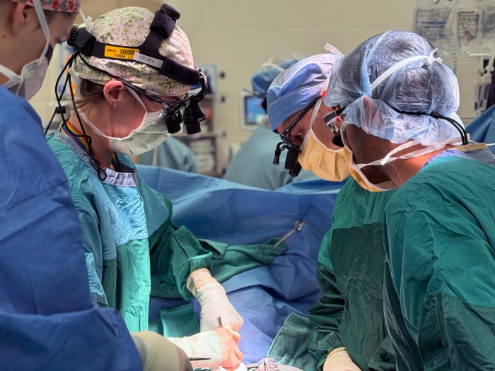 surgeons up close in surgery with scrubs and scrub hats on green teal