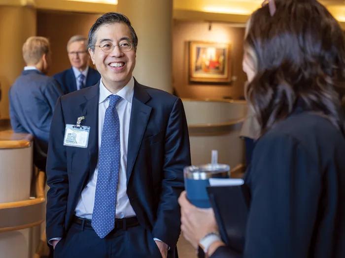 Medical School dean Tommy J. Wang is talking to someone at a meet and greet. He's facing the camera and smiling, but looking at the other person.