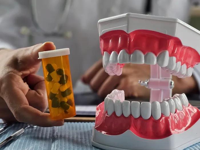 pill bottle next to fake mouth of teeth and gums