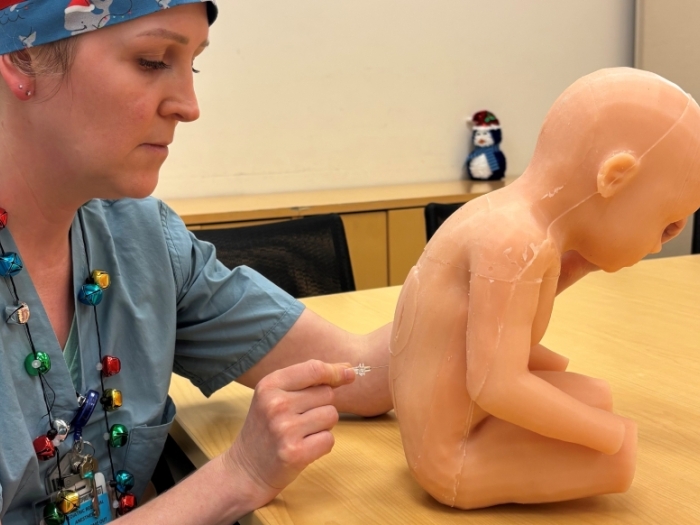 doctor in scrubs with doll baby doing spinal tap in back in conference room on table