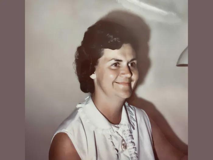 Portrait of Rose Page. She has short black hair and is wearing a sleeveless white blouse. She is smiling and turned 45 degrees to the right of the viewer.