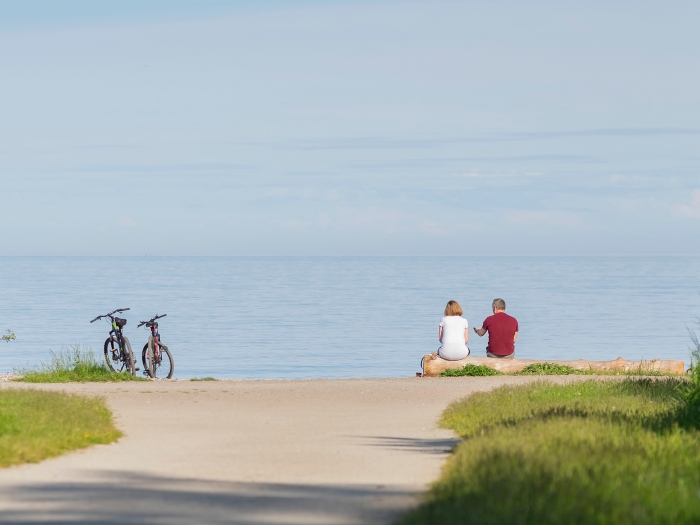couple in distance with bikes by water and green 