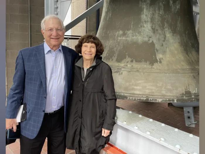 Stephen and Faith Brown standing together next to a huge bell at the top of Burton Memorial Tower.