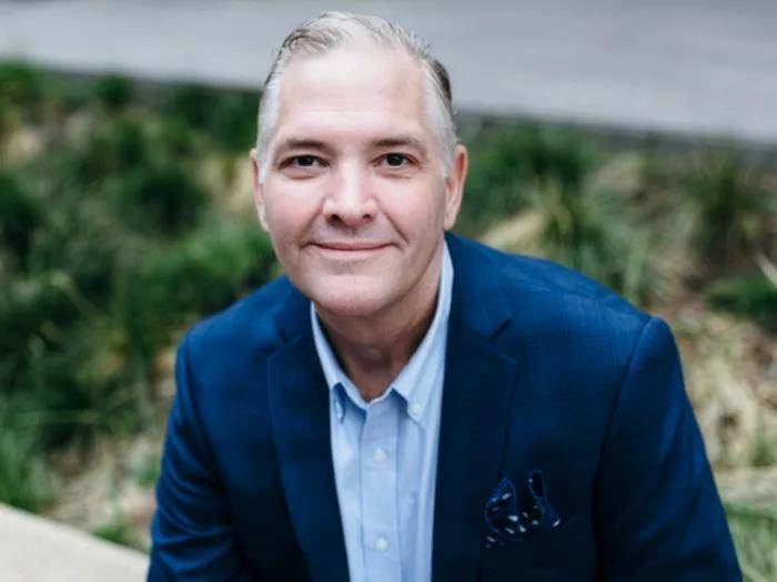 Portrait of Thomas Macek. He's wearing a navy blazer and light blue button-down shirt.